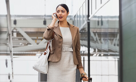 Geschäftsfrau telefoniert in einem internationalen Flughafen am Handy