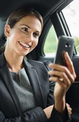 Business-Frau sitzt im Auto und guckt auf ihr Smartphone