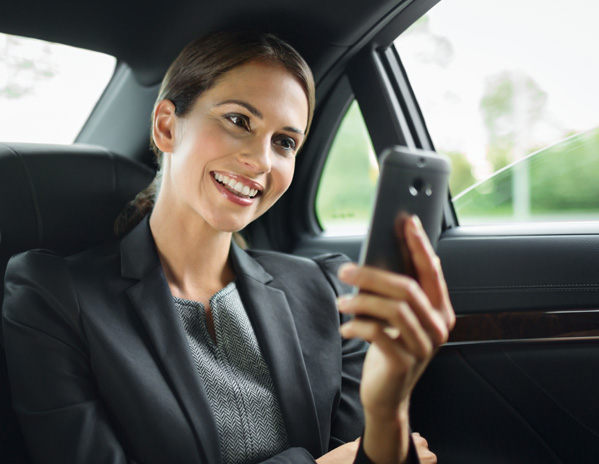 Eine Business-Frau sitzt im Auto und liest eine SMS.