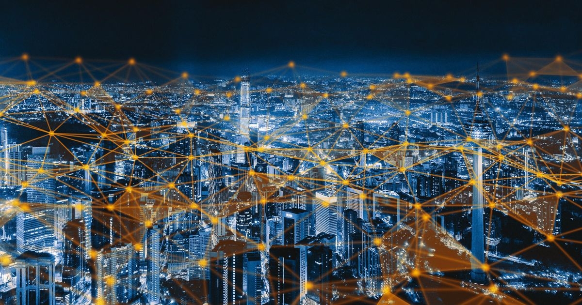 Blick auf eine Stadt bei Nacht, in der alle Geräte symbolisch per IoT-Cloud vernetzt sind
