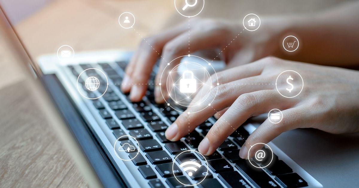 Hände, die auf der Tastatur eines Laptops tippen. Im Vordergrund schweben mehrere Symbole für Cybersicherheit.