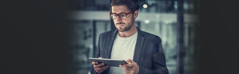 Mann mit Brille und Anzug hält iPad in der Hand