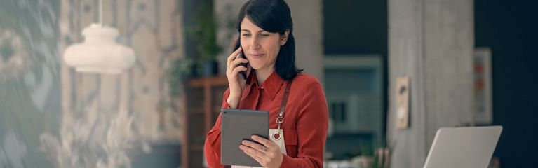 Frau telefoniert und hält Tablet in der Hand