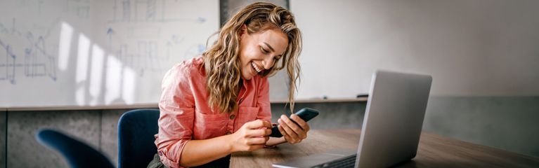 Frau im Büro lacht in ihr Handy
