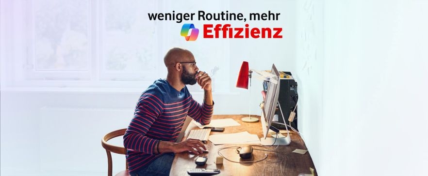 Person arbeitet an einem Schreibtisch vor einem Computer in einer hellen Büroumgebung mit Fenster. Oben rechts sind das Copilot-Logo sowie der Schriftzug „Weniger Routine, mehr Effizienz“ zu sehen.