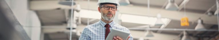 Mann mit Helm schaut auf sein Tablet