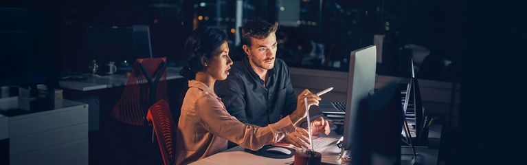 Zwei Personen sitzen am Abend gemeinsam im Büro