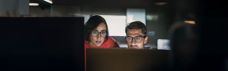 Frau und Mann abends im Büro