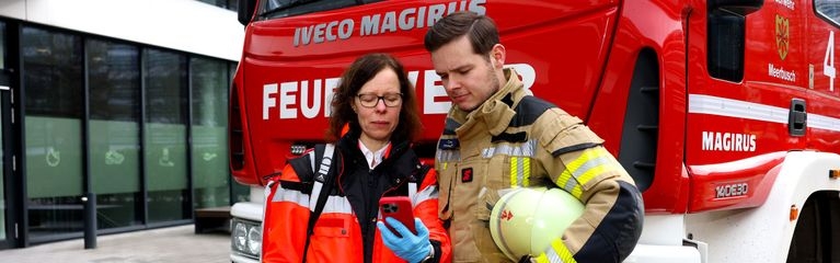 2 Menschen vor einem Feuerwehrauto