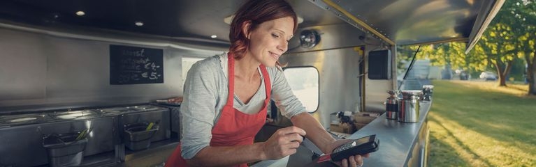 Frau im Imbisswagen mit EC-Kartenlese-Gerät