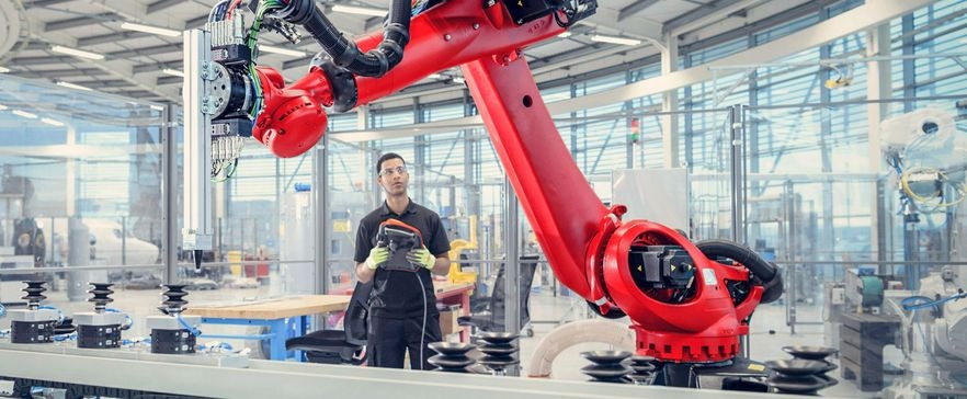 Mann mit Roboter in einer Fabrik