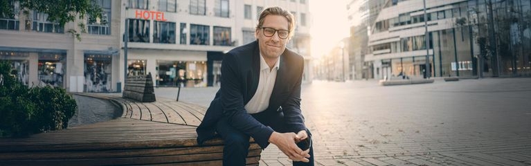 Mann sitzt auf einer Bank in der Innenstadt