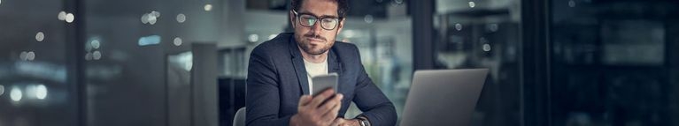 Mann mit Handy und Laptop im Büro