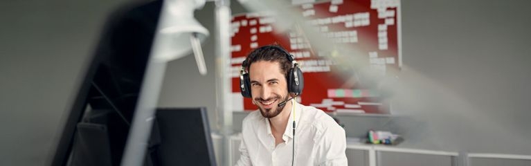 Mann mit Headset in weißem Hemd im Büro