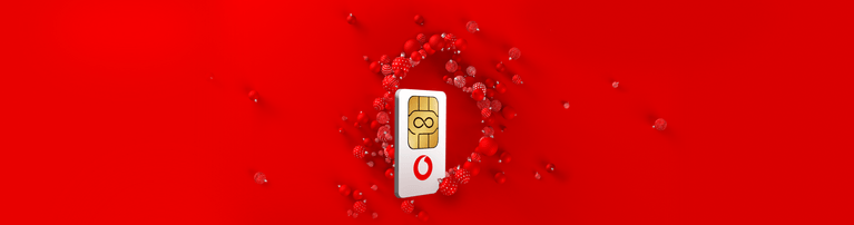 Vodafone SIM-Karte mit goldenem Chip auf rotem Hintergrund, umgeben von kleinen roten dekorativen Kugeln.