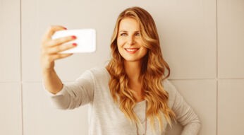 Frau schaltet Smartphone mit Gesichtserkennung frei.