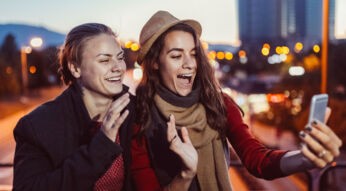 Zwei Freundinnen lächeln in die Smartphone-Kamera.