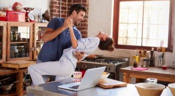 Mann und Frau tanzen zu Musik in der Küche