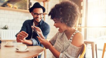 Lachende Frau mit Smartphone im Cafe