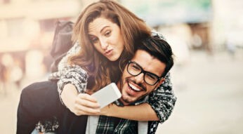 Junger Mann trägt Frau Huckepack.