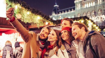 Freunde machen Selfie von sich auf einem Weihnachtsmarkt.