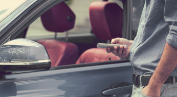 Ein Mann öffnet sein Fahrzeug mit dem Smartphone