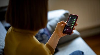 Frau hält iPhone in der Hand und checkt Aktienkurse