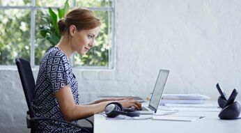 Junge Frau sitzt am Schreibtisch und arbeitet am Laptop