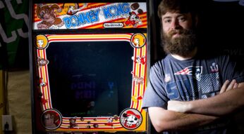 Ein Mann steht neben einem Donkey Kong Arcade-Spielautomaten