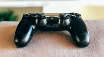 Schwarzer PS4-Controller liegt auf der Couch.