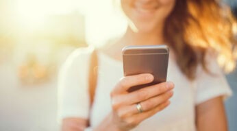 Junge Frau kontrolliert die Tiefenschärfe ihrer Smartphone-Bilder.