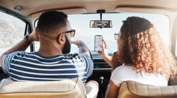 Paar nutzt im Auto eine Karten-App zur Navigation.