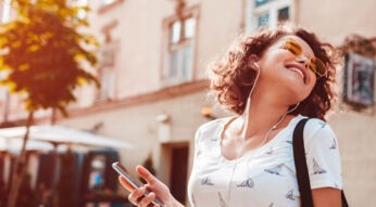 Junge Frau hört Inhalte von Apple Music übers iPhone.