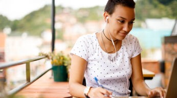 Junge Frau hört am MacBook via iTunes Musik.