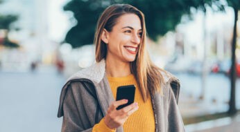 Frau hält Smartphone in der Hand, auf dem sie Harry Potter:Wizards Unite spielt.