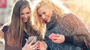 Freundinnen informieren sich am Smartphone über die Übertragung von Threema-IDs.