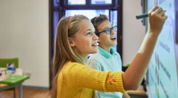 Zwei Schüler schreiben auf ein Smartboard - Bildung in der Digitalisierung zum Tag der Jugend