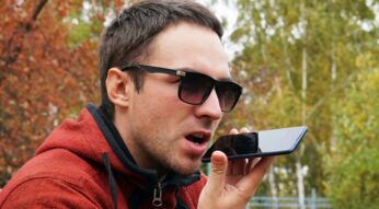 Junger Mann spricht am iPhone mit Siri, um Musik abzuspielen.