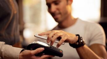 Mann zahlt kontaktlos via Google Pay auf dem Smartphone.