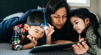 Eine Mutter surft mit ihren Kindern zuhause auf einem Tablet