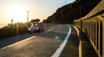 In Reise-Dokus fährt ein weißes Auto im Abendlicht auf einer Straße