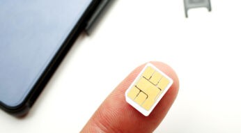 SIM-Karte auf Finger mit Handy im Hintergrund