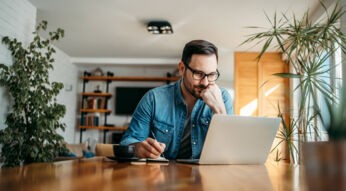Mann sitzt im Wohnzimmer al Laptop