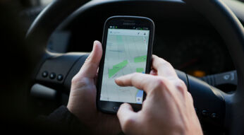 Person nutzt Google Maps auf dem Smartphone im Auto