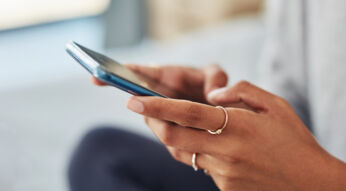 Zwei Hände einer jungen Frau scrollen auf einem Smartphone.