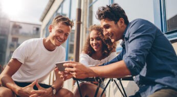 Eine Gruppe junger Menschen schaut sich amüsiert etwas auf dem Smartphone an