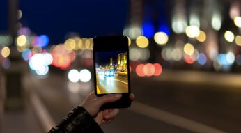 Frau macht mit dem Smartphone ein Foto bei Nacht