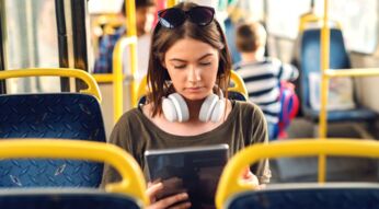 Frau sitzt mit 5G-Tablet im Bus.