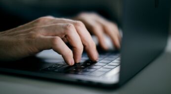 Männliche Hände tippen auf MacBook-Tastatur