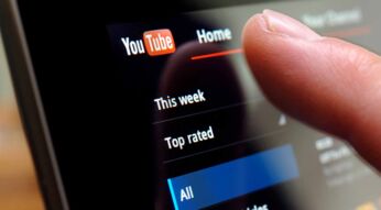 Ein Finger tipps auf einen Bildschirm bei geöffneter YouTube-App